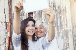 Mutter und Erwachsene Tochter nehmen ein Selfie draußen foto