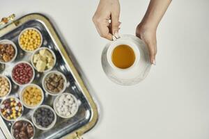 Frau Hände halten ein Tasse von Tee Über traditionell Arabisch iftar Süßigkeiten und Snacks foto