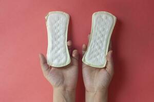 Frau Hände halten zwei feminin Hygiene Pads. Hände von weiblich halt Menstruation- Pads oder sanitär Servietten zum Frauen foto