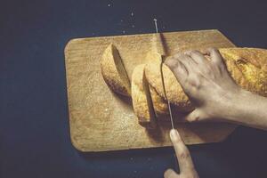 Essen Konzept. Hand Schneiden Brot. Schneiden ein Brot. oben Sicht. foto