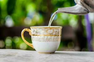 Tasse Tee schön mit Kessel gießen Tee auf Tabelle foto