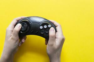 männlich Hand hält ein Joystick zum Video Spiele auf ein Gelb Hintergrund. Gamepad im das mans Hand auf ein Gelb Hintergrund foto