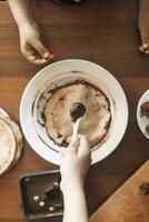 ein wenig Junge mit seine Mutter vorbereiten zusammen ein Frühstück. Mutter und Sohn verschmieren Schokolade Sahne zu dünn Pfannkuchen. kostenlos Raum foto