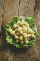 ein Teller von gekocht Neu frisch Kartoffeln auf hölzern Hintergrund. kostenlos Raum foto