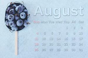 August Kalender. Stapel von gefroren Süss Kirschen mit August Monat Kalender. Sommer- foto