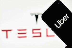 ein Person hält Smartphone mit über Warenzeichen mit Tesla Logo foto