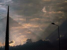 groß Turm Suspension Brücke und Laternenpfahl beim wolkig Sonnenuntergang foto