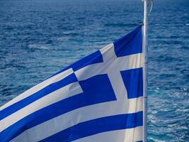 griechisch Flagge im das Wind und schön Meer im das Hintergrund foto