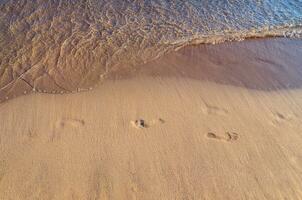 Fußabdrücke auf ein leeren tropisch sandig Strand foto