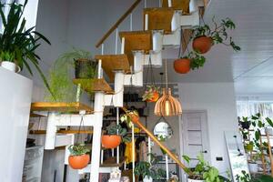 modular Metall Treppe mit hölzern Schritte im das Weiß Innere von ein Grün Haus mit eingetopft Pflanzen, hängend Blumentopf, Lampenschirm foto