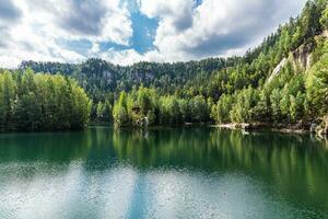 Grün Wasser von Ruhe Wald See zwischen klein Berge bedeckt mit Wald foto