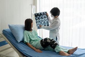 Orthopäde zeigt einem Patienten mit einer Knieverletzung durch einen Unfall ein MRT foto
