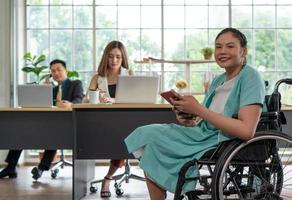 Junge behinderte Frau sitzt im Rollstuhl mit Kollegen im Büro