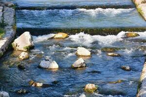 ein Fluss mit Felsen und Wasser fließend durch es foto