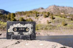 ein alt Kassette Band Sitzung auf oben von ein Felsen in der Nähe von ein See foto