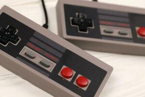 charkow, ukraine - 27. dezember 2020 zwei alte gamepads für 8-bit-videospielkonsolen nintendo entertainment system und nes mini auf weißem tisch. Retro-Spiele der alten Schule foto