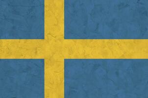 schwedenfahne in hellen farben auf alter reliefputzwand dargestellt. strukturierte Fahne auf rauem Hintergrund foto