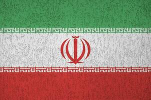 die iranische flagge ist in hellen farben auf einer alten reliefputzwand dargestellt. strukturierte Fahne auf rauem Hintergrund foto