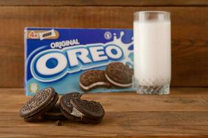 viele Oreo Sandwich Sahne Kekse mit Pack und Milch Glas auf hölzern Hintergrund foto