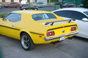 zurück Aussicht von Ford Mustang mach 1 im hell Gelb Farbe auf Öffentlichkeit Parkplatz Platz foto