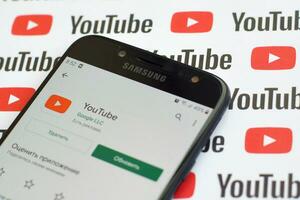 Youtube App auf Samsung Smartphone Bildschirm auf Papier Banner mit klein Youtube Logos und Inschriften. Youtube ist Google Tochtergesellschaft und amerikanisch die meisten Beliebt Video teilen Plattform foto