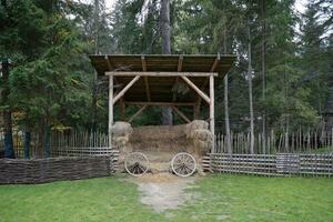 Platz mit Stapel von Heu Würfel und rustikal hölzern Räder von alt Wagen foto