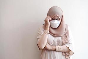 Muslime, die eine chirurgische Maske tragen und sich auf pastellfarbenem Hintergrund krank fühlen. foto