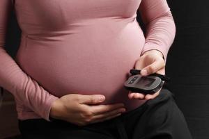 Schwangere Frau mit Blutzuckermessgerät, Schwangerschaftsgesundheit foto