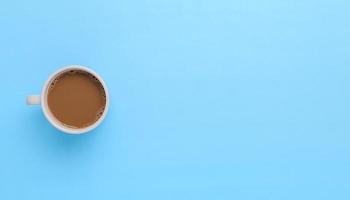 Hand hält eine Kaffeetasse auf blauem Hintergrund foto