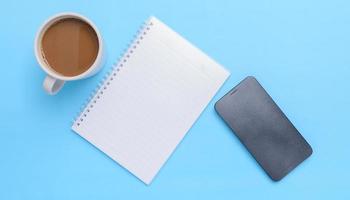 Kaffeetasse, Buch, Smartphone auf blauem Hintergrund foto