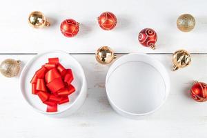 Geschenkboxen mit rotem Band und Weihnachtskugeln auf weißem Hintergrund.