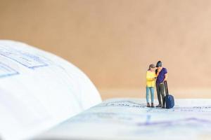 Miniatur-Leute-Paar, das auf einem Pass mit Einreisestempel steht foto