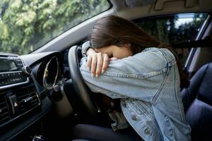 asiatisch Mädchen betont oder müde im Auto Lügen auf Lenkung Rad foto