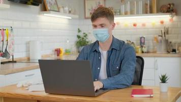 Quarantäne-, Remote-Job- und Pandemie-Konzept - Mann mittleren Alters mit medizinischer Gesichtsschutzmaske zum Schutz vor Viruserkrankungen mit Laptop, der zu Hause arbeitet foto