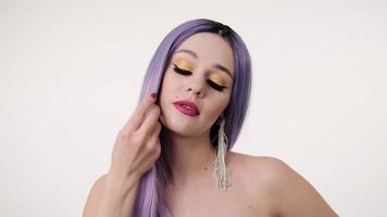 Nahaufnahmeporträt einer süßen Frau mit lila Perücke und schönem Make-up auf hellem Hintergrund.