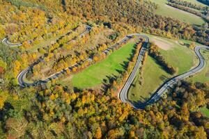 schön Antenne Landschaft von Berg Wald Straße. Antenne Aussicht von kurvig Straße im schön Herbst Wald foto