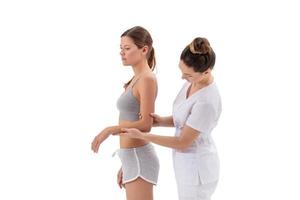Arzt Physiotherapeut streckt eine junge Sportfrau isoliert auf weißem Hintergrund foto