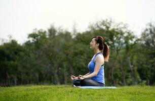 jung attraktiv Frau tun Yoga, ruhig und glücklich Verstand im das Grün Natur Park, Konzept zum nehmen Pflege physisch Gesundheit, geistig Gesundheit und Spiritualität foto