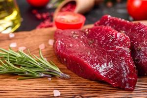 frisches rohes Rindersteak Mignon, mit Salz, Pfefferkörner, Thymian, Tomaten foto