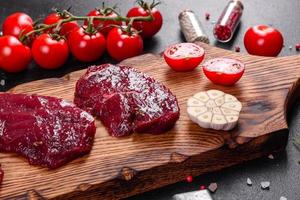 frisches rohes Rindersteak Mignon, mit Salz, Pfefferkörner, Thymian, Tomaten foto
