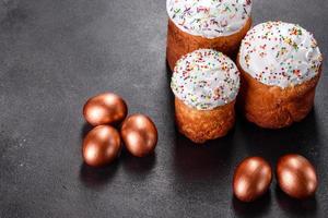 Ostereier Gold und Bronze und Osterkuchen auf dunklem Hintergrund foto