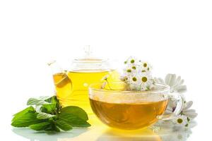 Kamille Blume Tee im Glas Tasse und Teekanne, auf Weiß Hintergrund. foto