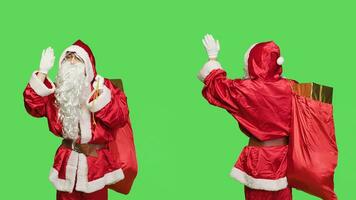 lächelnd Santa Gruß Menschen auf Kamera, winken Hallo und Schauspielkunst heiter Gefühl glücklich Verbreitung Urlaub Geist. Vater Weihnachten mit Tasche voll von Geschenke Kisten feiern saisonal Winter Fall. foto