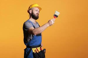 männlich Auftragnehmer halten Pinsel zu Farbe Wände, Arbeiten auf Sanierung Projekt und Gemälde mit Werkzeug. Konstruktion Arbeiter Maler tun Renovierung Arbeit mit Bürste und malen. foto