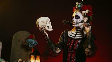 Grusel weiblich Modell- Schauspielkunst flirty mit Schädel und schwarz Rosen, tragen traditionell Körper Kunst zu feiern Mexikaner Urlaub. suchen mögen Göttin von Tod auf Dios de los Muertos Ritual. Handheld Schuss. foto