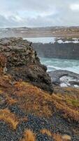 Fantastisch gullfoss Wasserfall im Island mit fest Fluss fließend aus Berg Rand, Nord Wildnis Natur. isländisch Landschaft mit Schnee bedeckt Felder und Wasser Strom Laufen Nieder Klippen. foto