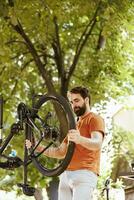Bild zeigen begeistert sportlich kaukasisch Mann packend und Prüfung beschädigt zerlegt Fahrrad Rad zum Reparatur. gesund jung aktiv männlich Radfahrer wieder anbringen Fahrrad Reifen Gummi. foto