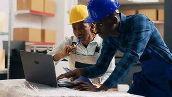 afrikanisch amerikanisch Angestellte lesen Produkte auf Laptop und suchen beim Waren verpackt im Karton Kisten im Depot. Warenhaus Manager und Arbeiter Überprüfung Lager Logistik, klein Geschäft. Handheld Schuss. foto