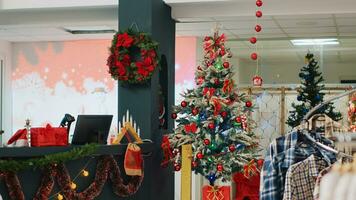 schön dekoriert Weihnachten Baum im Kleidung Geschäft bereit zu Verbreitung Urlaub jubeln zu Besuch Kunden suchen zu Kaufen die Geschenke. Weihnachten schmücken Mode Boutique im Einkaufszentrum während Winter Urlaub Jahreszeit foto