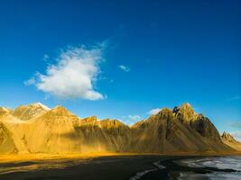 Arktis stokksnes schwarz Sand Strand mit fest steil Vestrahorn Berge Erstellen Fantastisch isländisch Umfeld. schön Ozean atlantisch Küste mit hoch Hügel auf Halbinsel im Island. foto